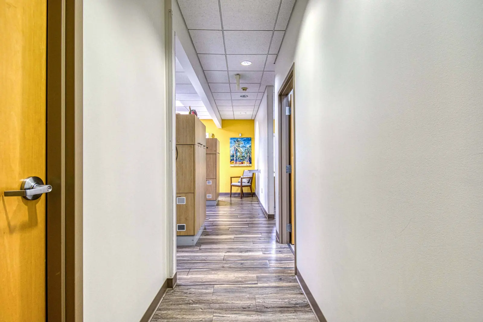 A warm-lit corridor running between treatment rooms