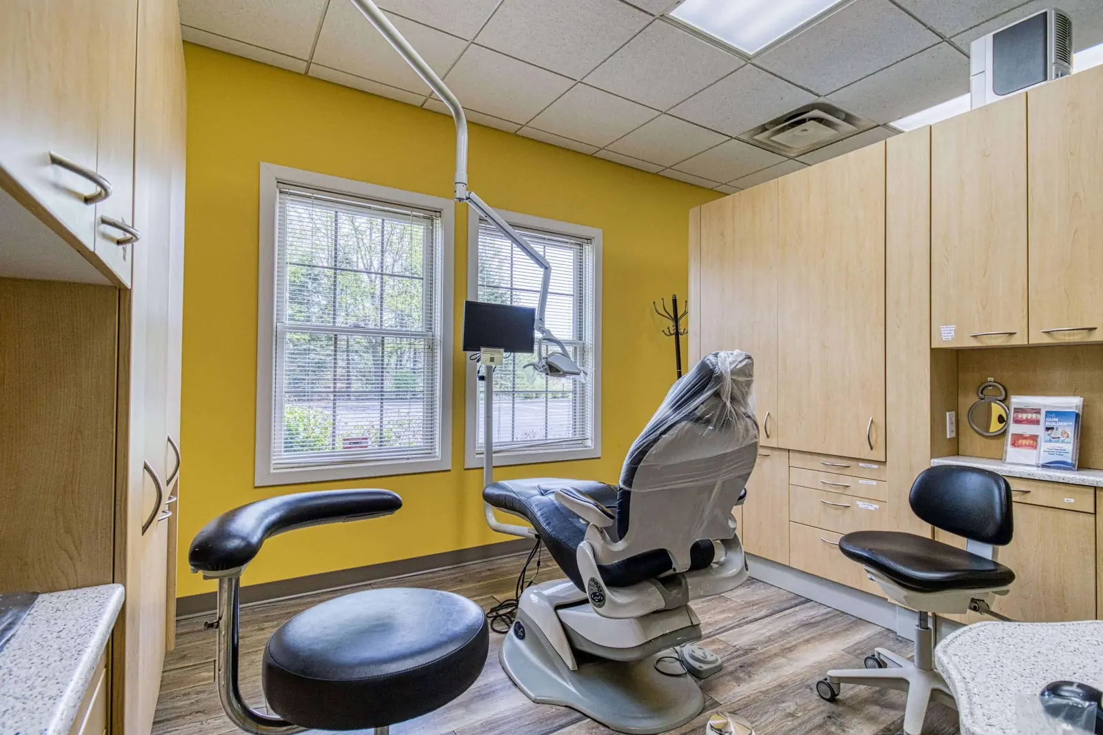 A corner treatment room with cabinetry and a wall-mounted screen