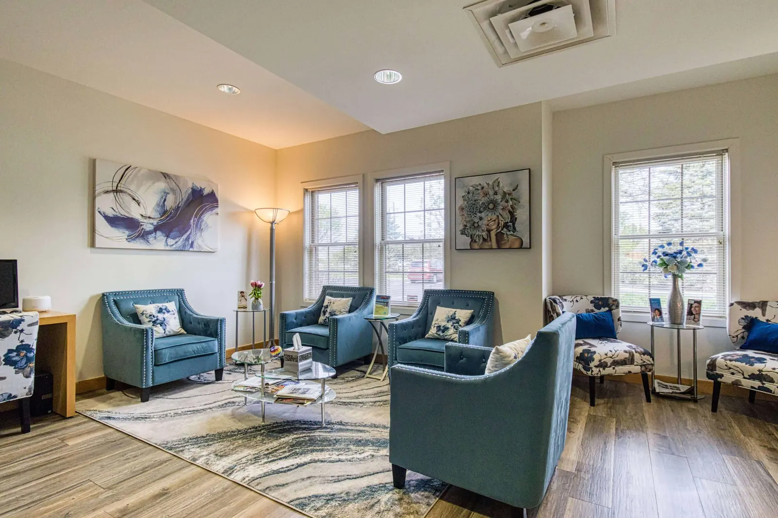 A practice waiting room with armchairs and daylight from tall windows