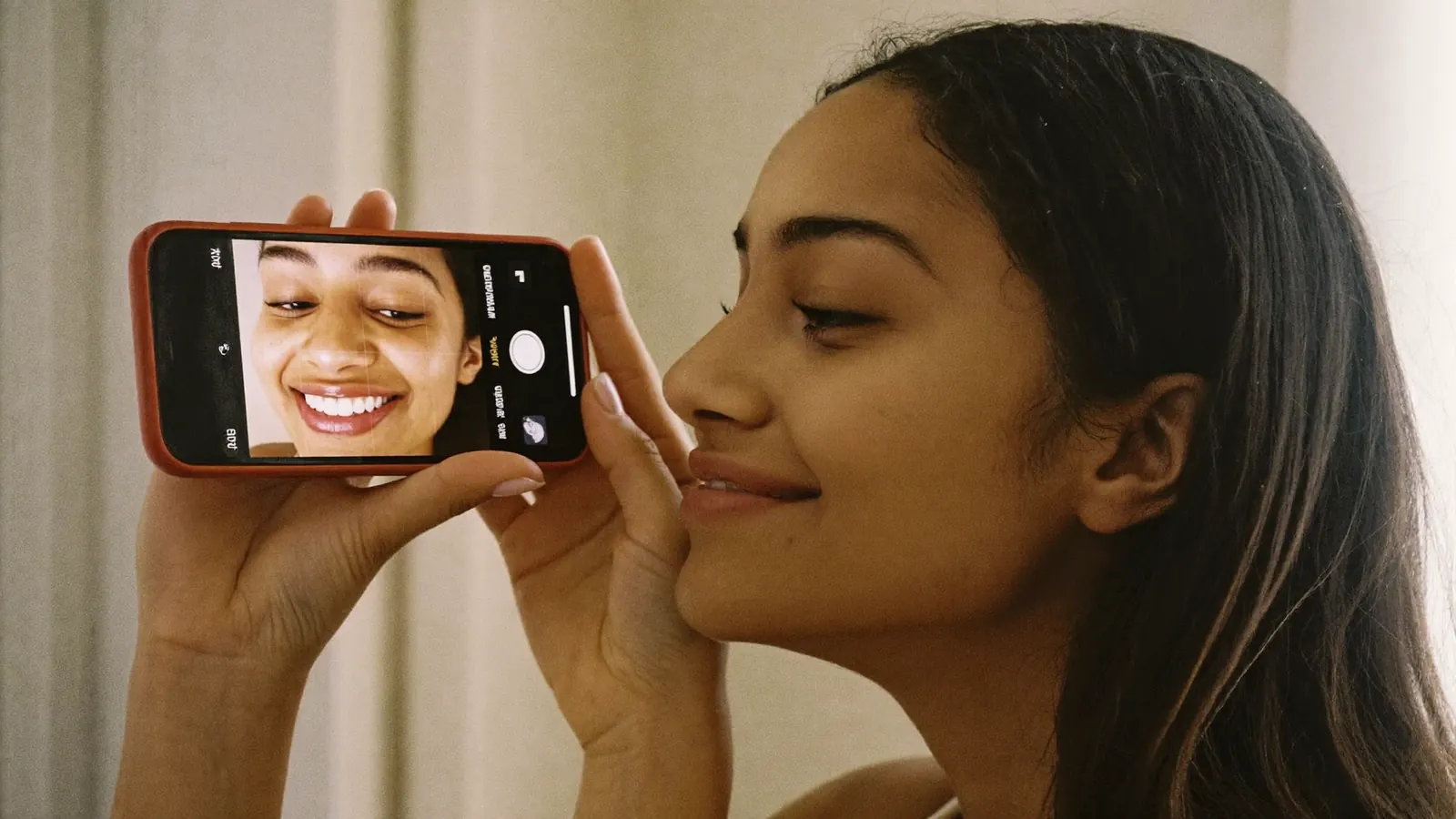 A woman checking her smile on her phone